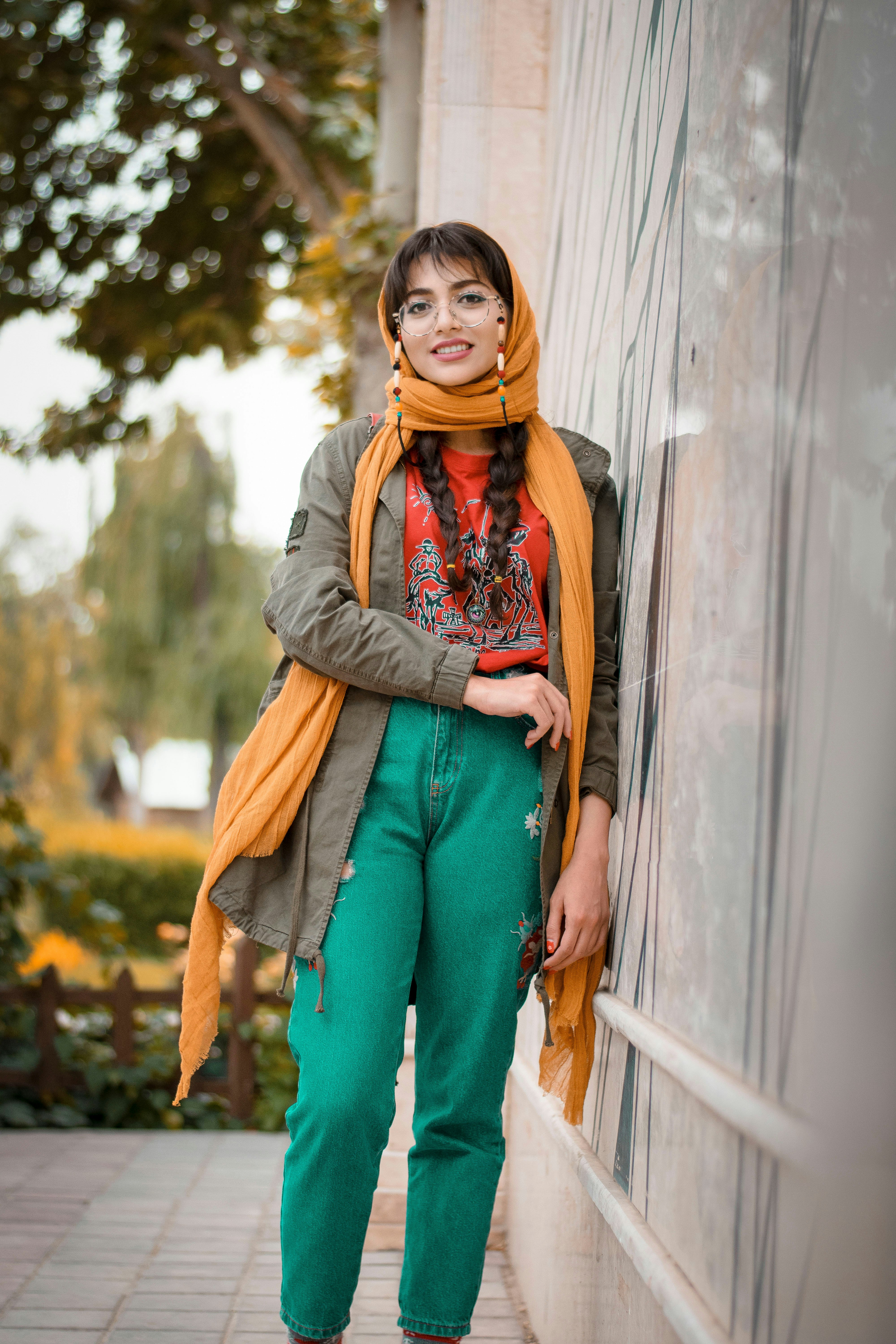 woman in gray scarf and brown coat standing beside gray wall